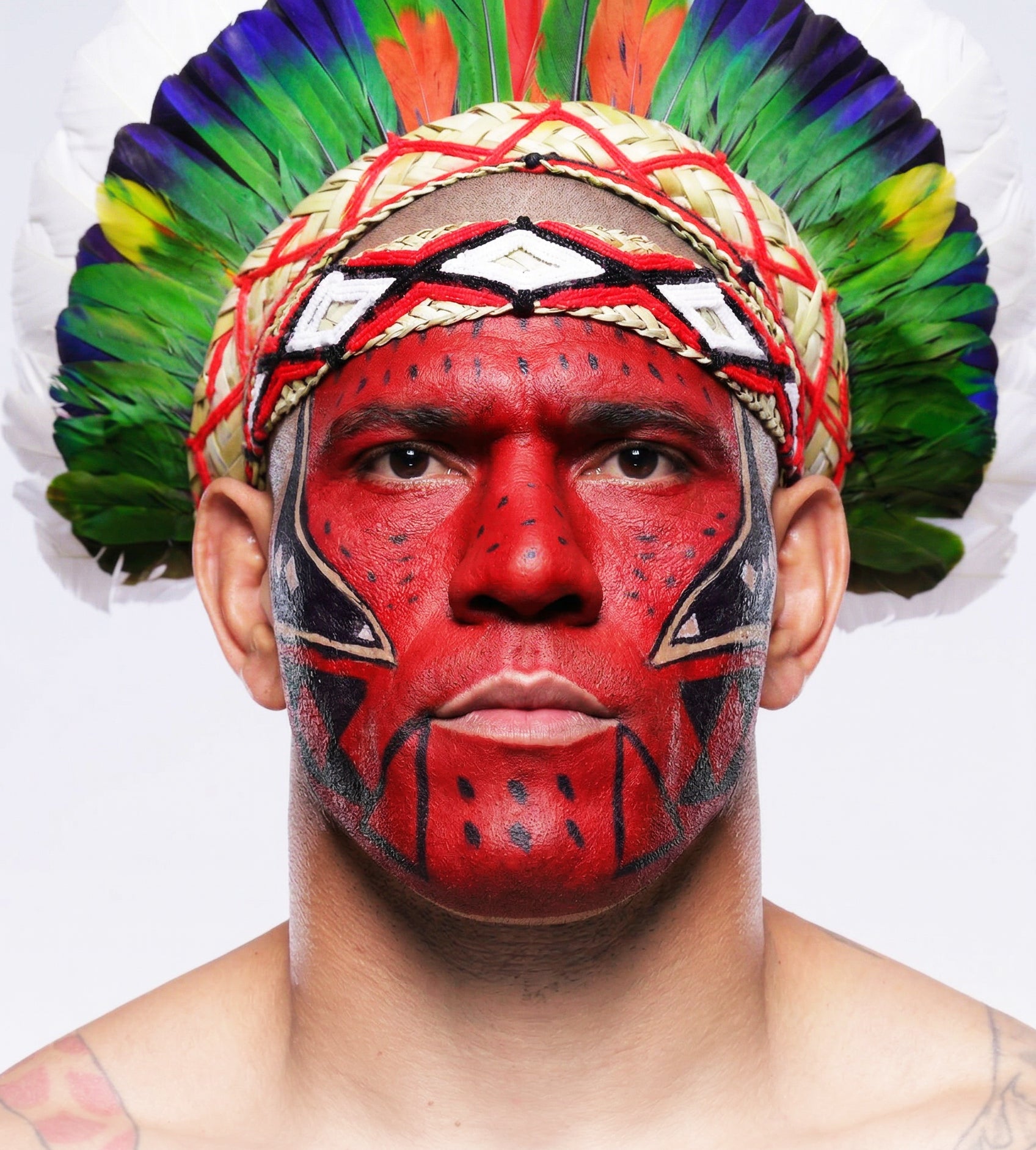 Alex Pereira with face paint and colorful headdress on a white background
