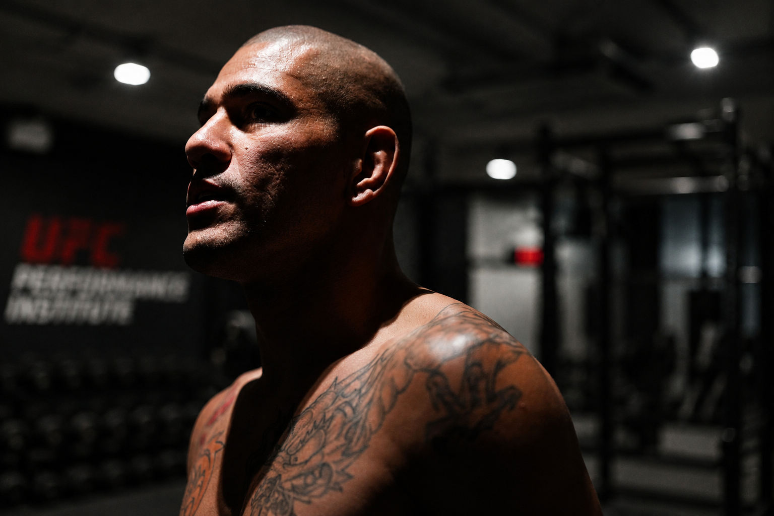 Man with tattoos in a dark gym setting 